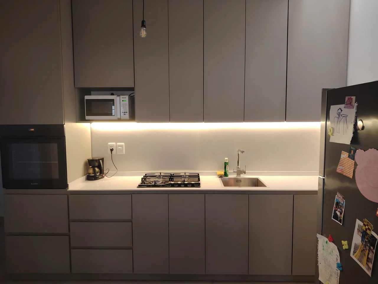 Cocina realizada por Alberto, con frentes grises, horno empotrado y mesada blanca.