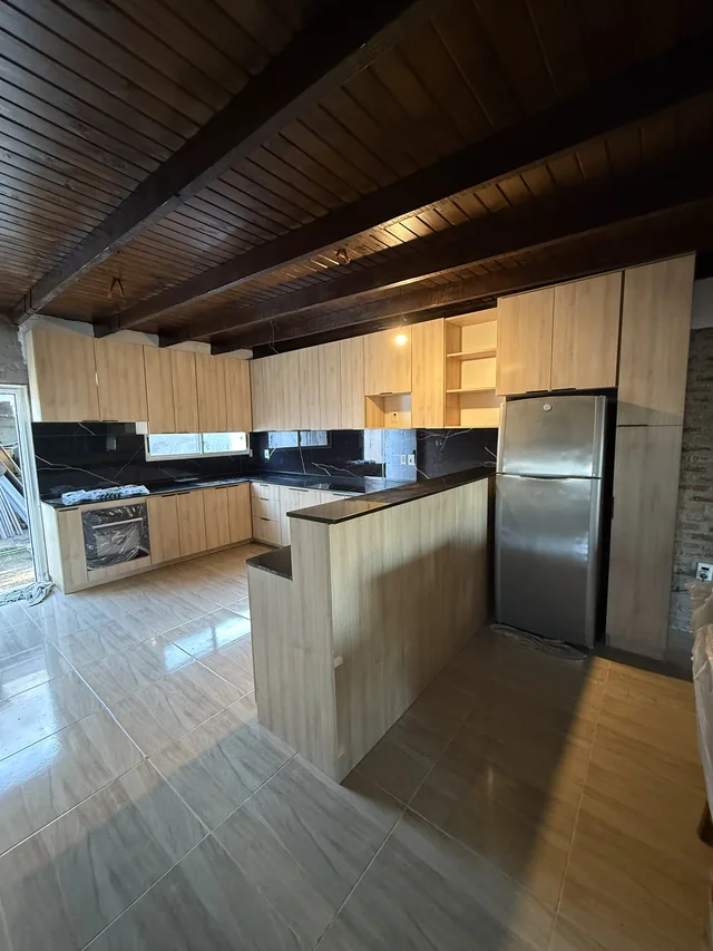 Cocina durante la instalación con muebles de aspecto madera, península y mesada oscura.