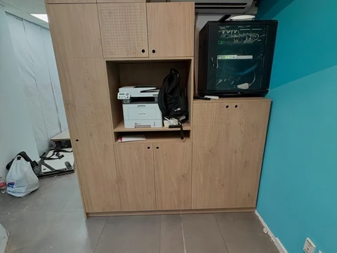 Mueble de oficina en tono madera con puertas, estantes, impresora y espacio contiguo para equipos de red.