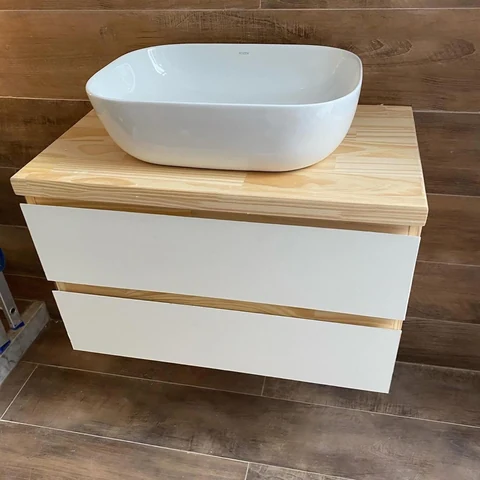 Mueble de baño suspendido con dos frentes blancos, cubierta de madera y bacha blanca de apoyo.
